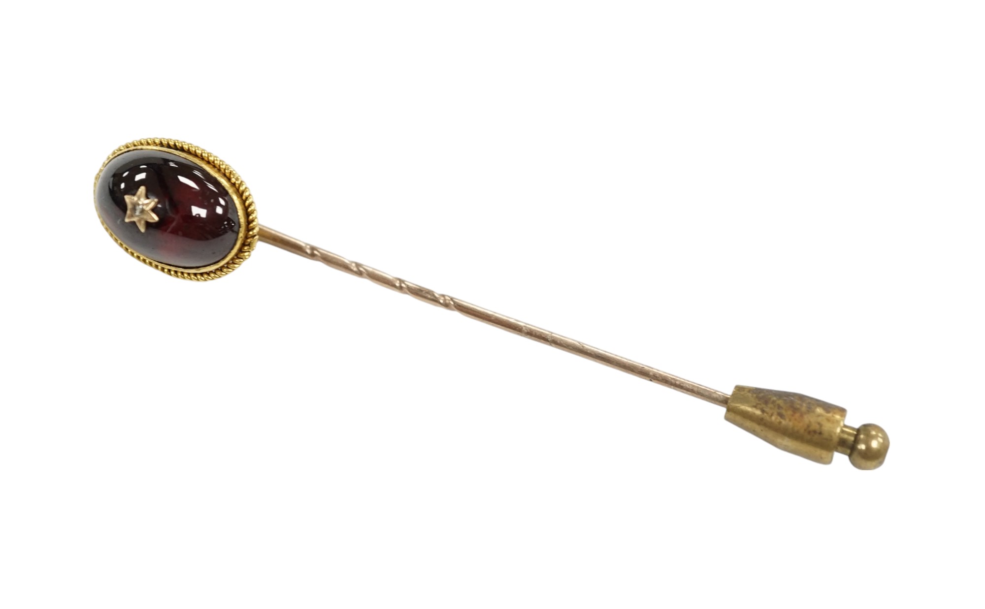 A cased Victorian yellow metal, oval cabochon garnet and diamond chip set stick pin, overall 77mm. Condition - fair